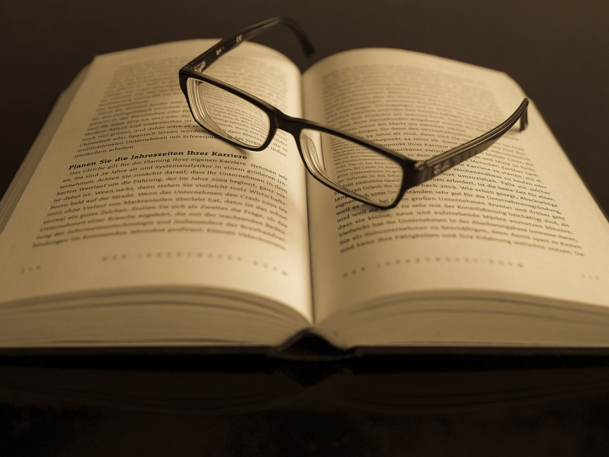Ein aufgeschlagenes Buch mit einer Brille drauf